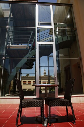 Een modern gebouw met grote glazen ramen, een trap en een tafel met twee stoelen erbuiten.