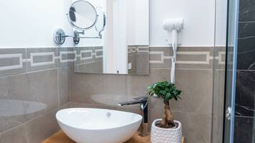Un baño con un lavamanos blanco, un espejo, un secador de pelo y una planta en maceta.