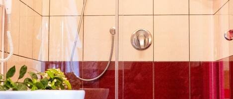 Un baño con un lavabo blanco, ducha y paredes con azulejos rojos.