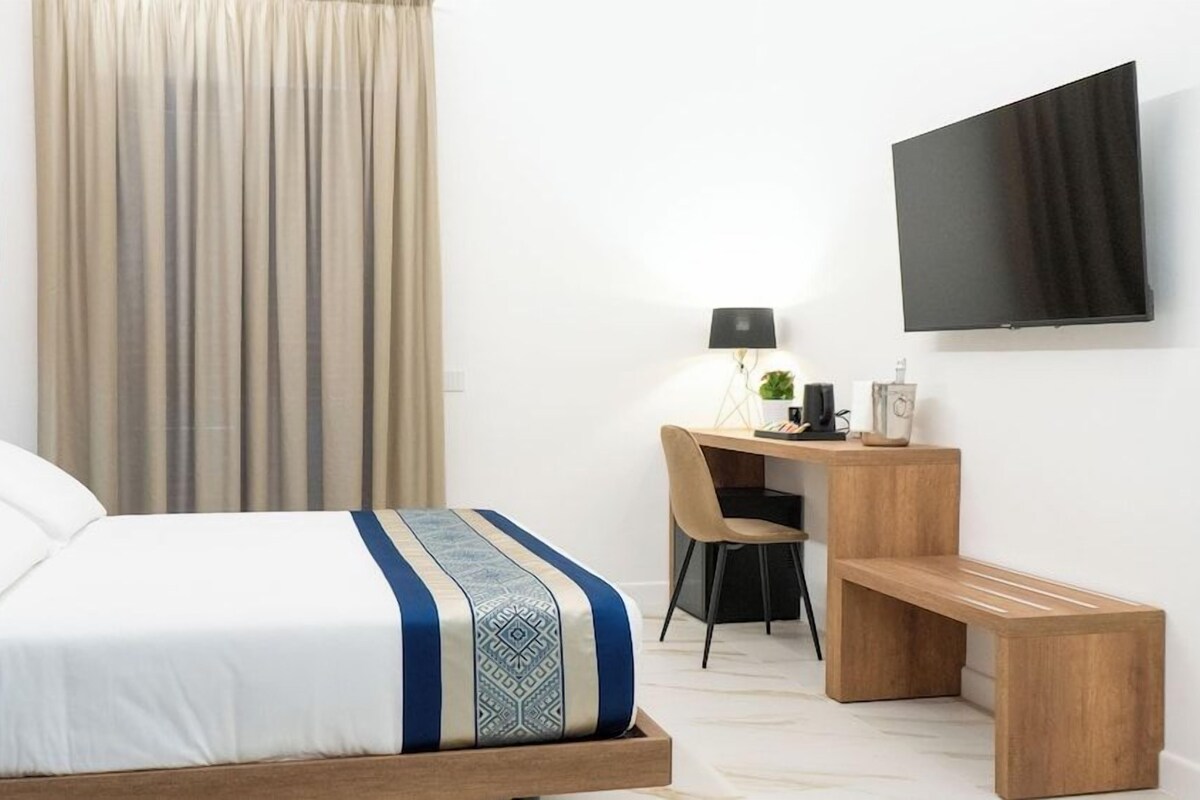 Een hotelkamer met een bed, een bureau, een stoel, een televisie en een bank.