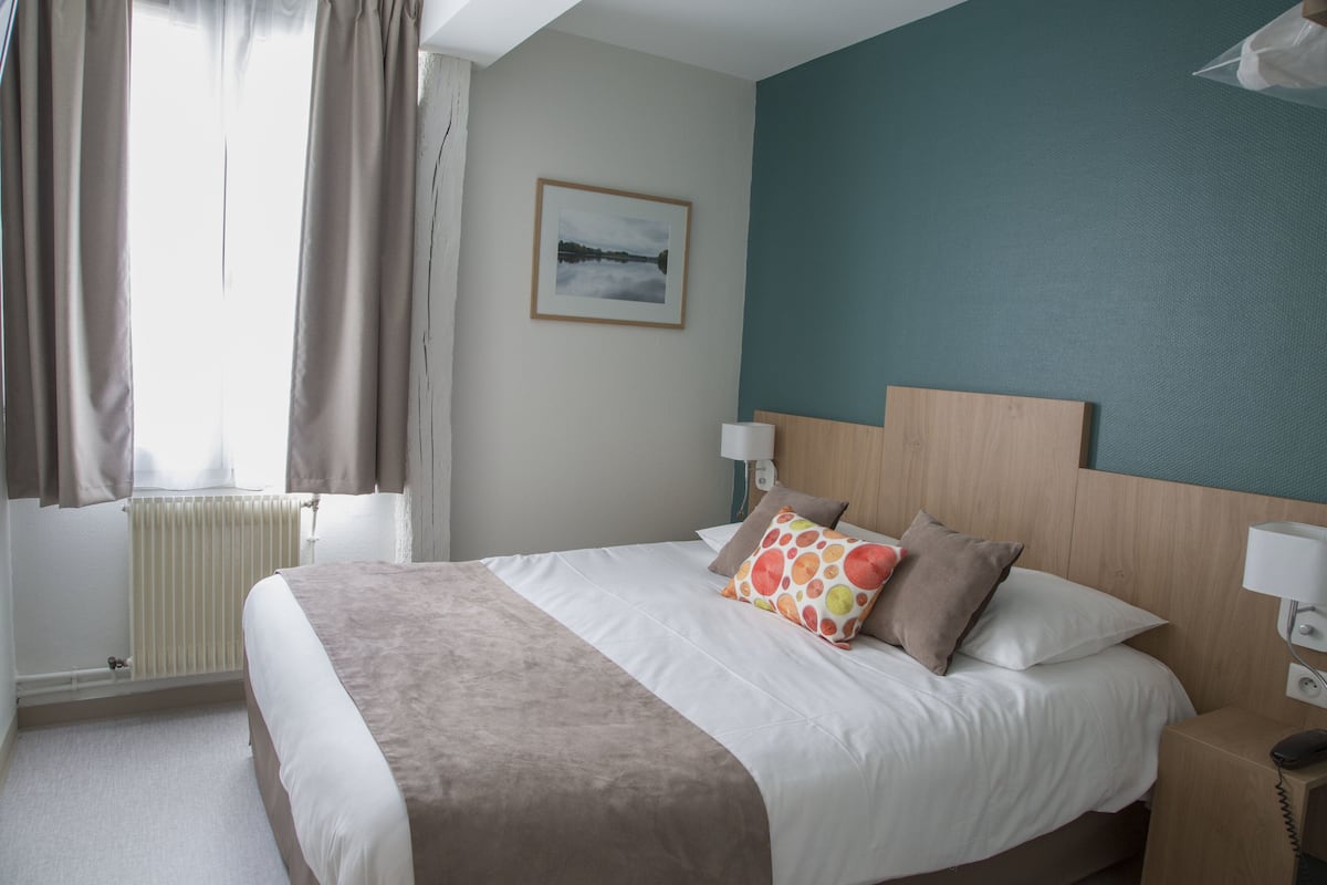 A neatly made bed with a white and brown bedspread, a wooden headboard, and two bedside lamps.