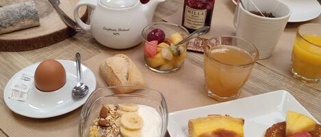 A breakfast table with various dishes including toast, fruit, a slice of quiche, and a glass of orange juice.