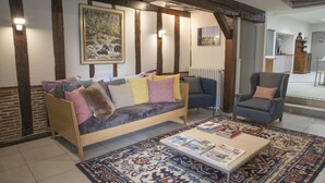 Una sala de estar acogedora con un sofá, un sillón y una mesa de centro con revistas.