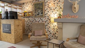 Un acogedor vestíbulo de hotel con un mostrador de recepción de madera, un sillón cómodo y un cartel que dice 'Welcome'.