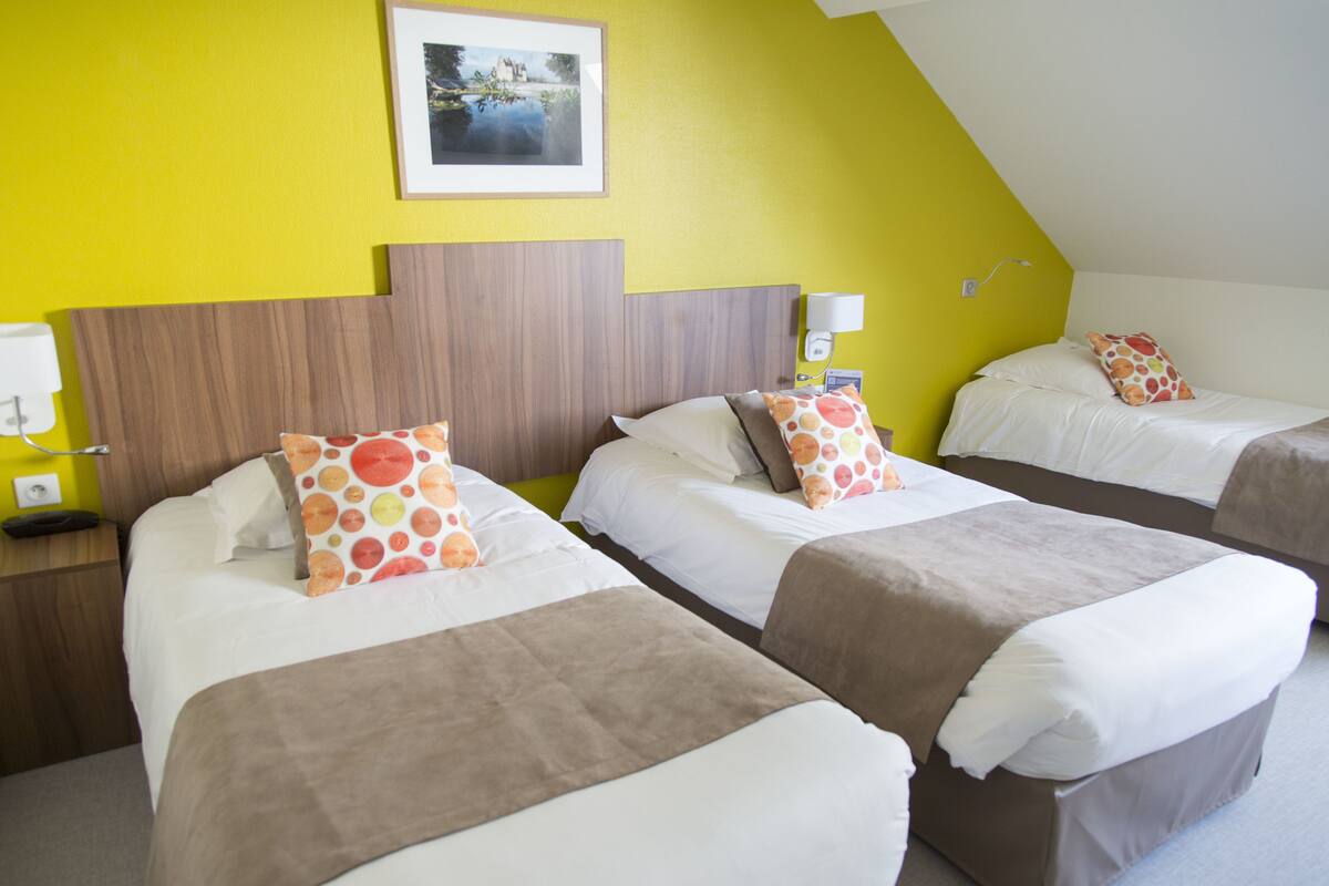 A hotel room with two beds, each with white bedding and orange polka dot pillows.