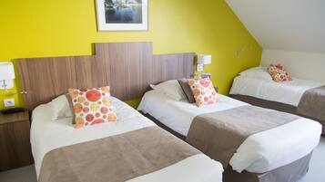 Une chambre d’hôtel avec deux lits, chacun agrémenté de draps blancs et d’oreillers à pois orange.