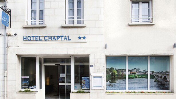 Un edificio con un letrero que dice "HOTEL CHAPTAL" y un amplio ventanal que muestra una vista panorámica de un río y un puente.