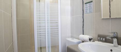 A modern bathroom with a shower, toilet, sink, and a mirror.