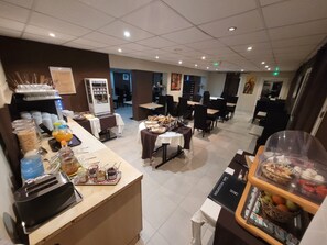 A hotel dining area with buffet stations, tables, and chairs. - Hôtel Le Cosy Blois Nord (Villebarou)