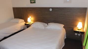 A hotel room with two single beds, each with a bedside table and a lamp.