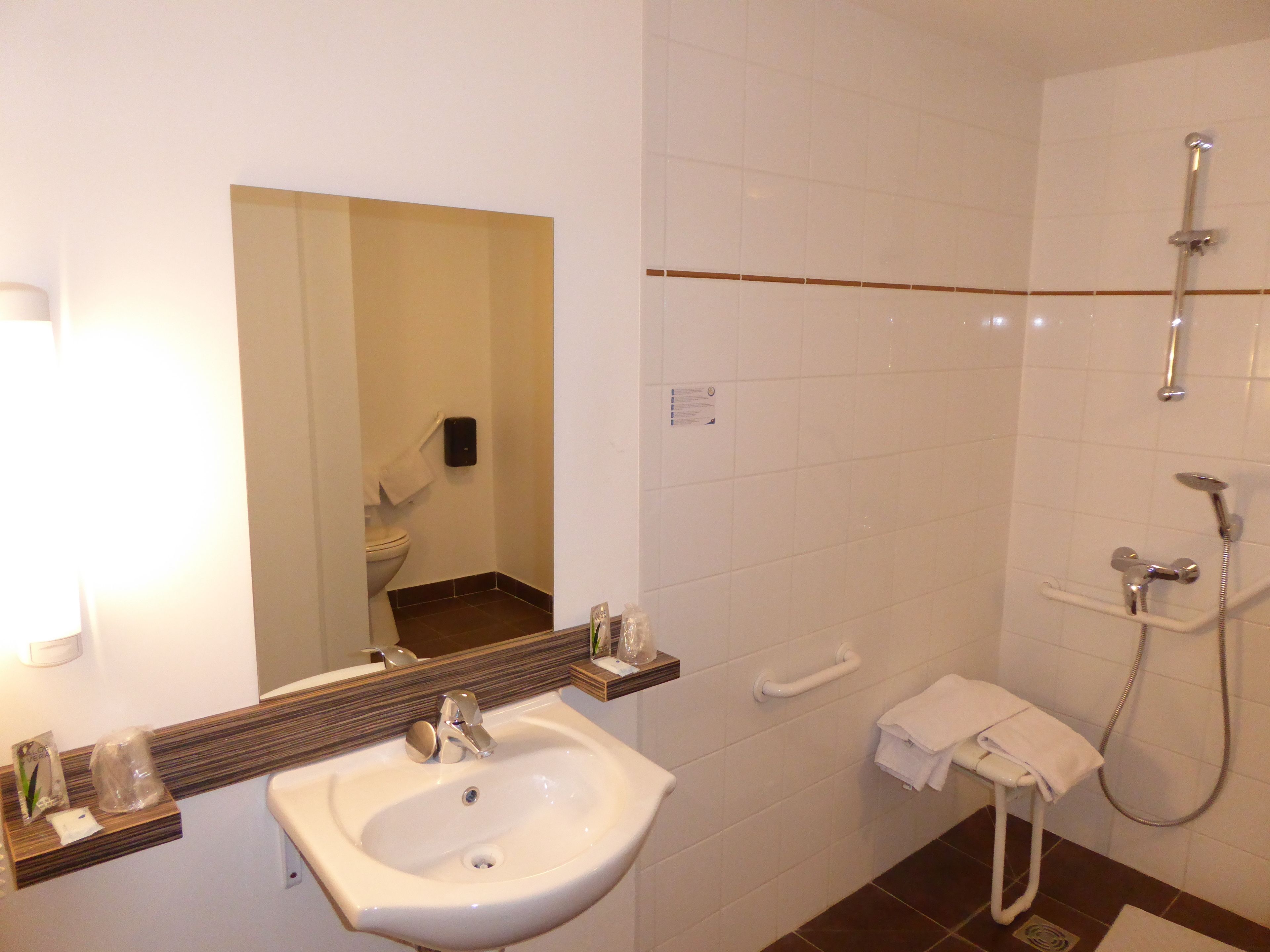 A bathroom with a sink, mirror, and shower.