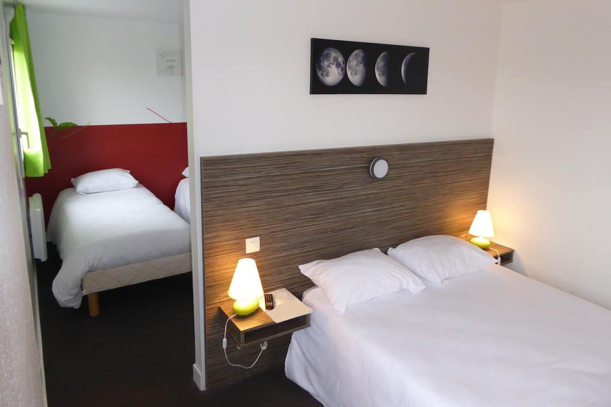A hotel room with two beds, a red accent wall, a wall-mounted picture of the moon phases, and bedside lamps.