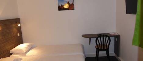 A hotel room with a bed, a desk, a chair, a TV, and a picture on the wall.