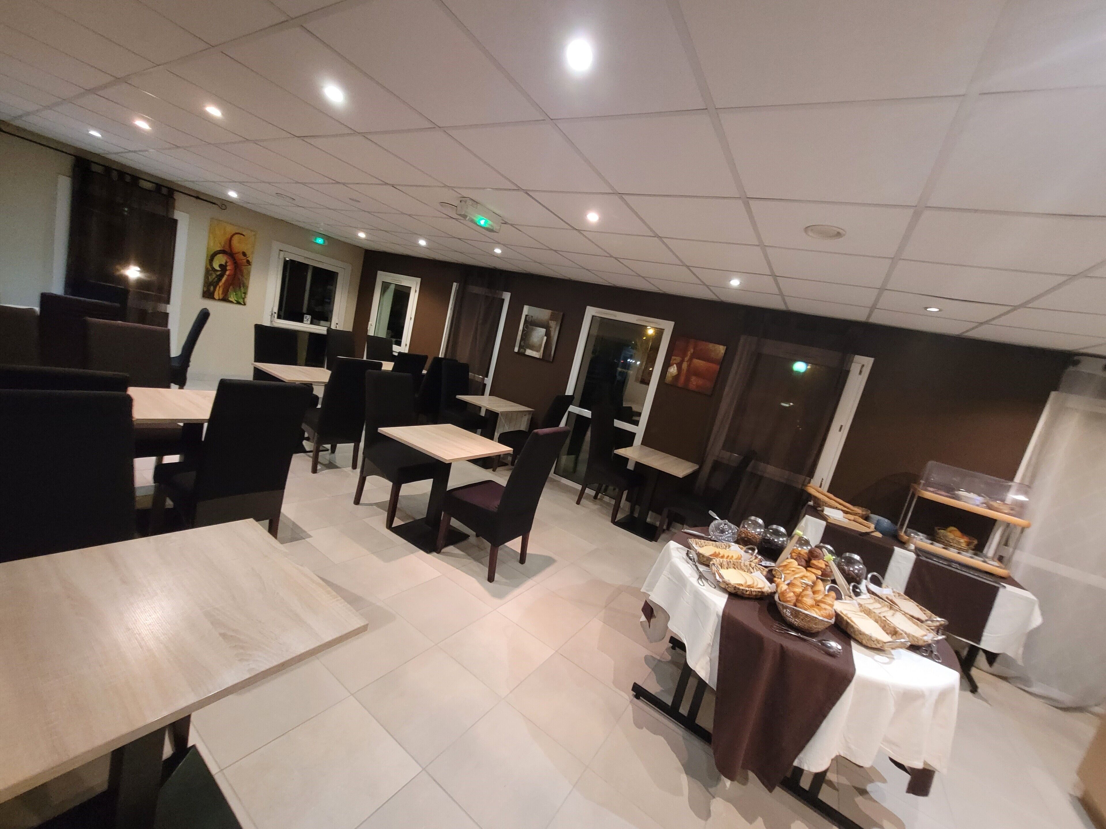 Ein Restaurant mit Sitzgelegenheiten in Form von Boxen und Tischen, einem Buffetbereich mit verschiedenen Speisen sowie einer Decke mit eingelassener Beleuchtung.