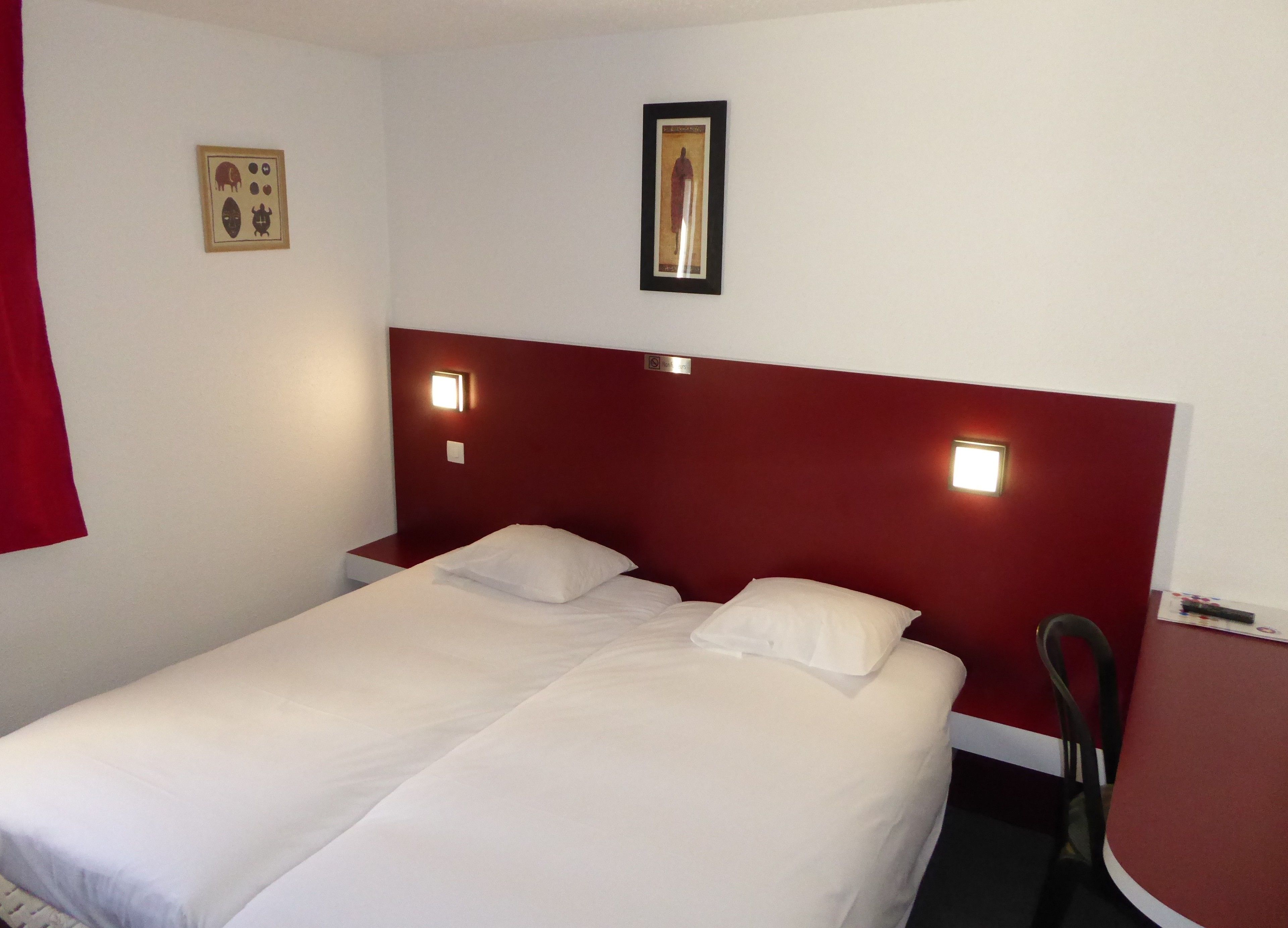 A hotel room with a single bed, two bedside tables, and a small desk with a chair.