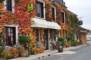 Un bâtiment aux murs recouverts de lierre et doté d’un auvent blanc.