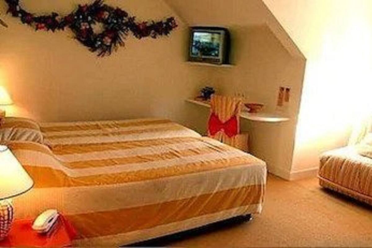 Un dormitorio con cama, mesita de noche, lámpara y un pequeño escritorio con silla.