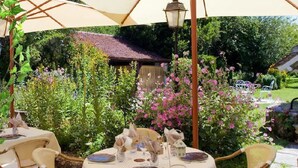 An outdoor dining area with round tables, chairs, and umbrellas. - LOGIS Auberge du Centre (Chitenay)