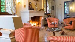 A cozy living room with striped armchairs, a fireplace, and a small table with a book and a glass. - LOGIS Auberge du Centre (Chitenay)