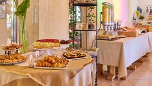 A buffet table with various food items, including pastries, cakes, and a tiered stand with condiments. - Hotel Ariston (Malcesine)