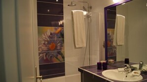 A bathroom with a shower, a sink, and a mirror. - Hôtel de la Cognette (Issoudun)
