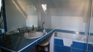 A bathroom with two sinks, a bathtub, and a large mirror. - Hôtel de la Cognette (Issoudun)