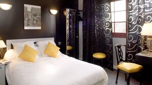 A hotel room with a large bed, two bedside lamps, a framed picture on the wall, and a window with curtains. - Hôtel de la Cognette (Issoudun)