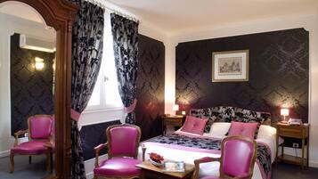 Une chambre avec un grand lit, deux tables de chevet, un miroir et deux chaises roses.