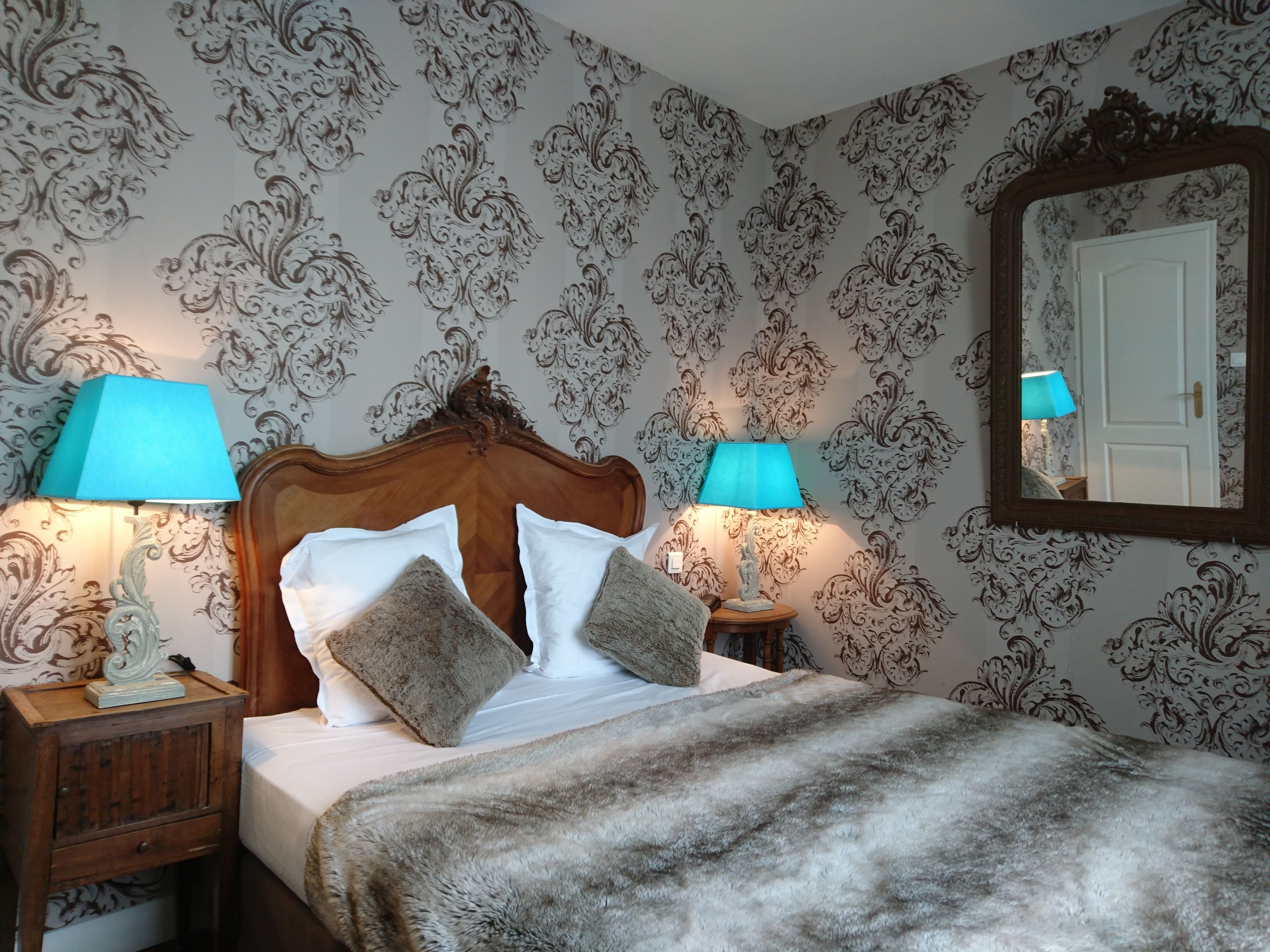 A neatly made bed with two pillows, a wooden headboard, and two bedside lamps.