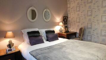 Una habitación de hotel con una cama, dos mesitas de noche, una silla y una pared decorada con cuadros.