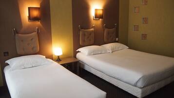 Une chambre d’hôtel avec deux lits simples, une table de chevet avec une lampe et un luminaire fixé au mur.
