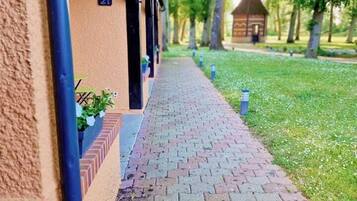 Guests can access their accommodations via a charming pathway lined with lush greenery and potted plants.