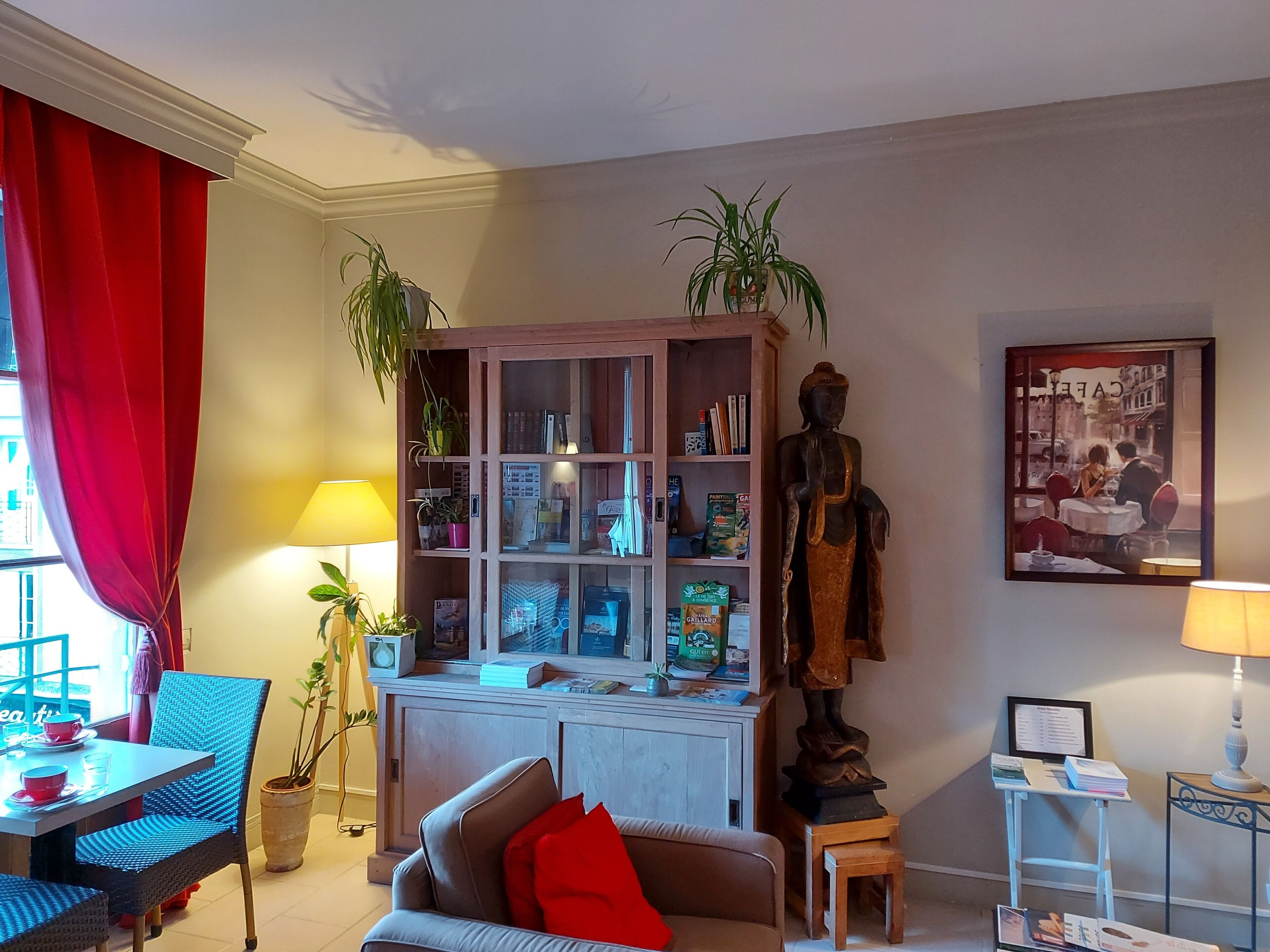 A living room with a sofa, a dining table, a cabinet with glass doors, and a Buddha statue.