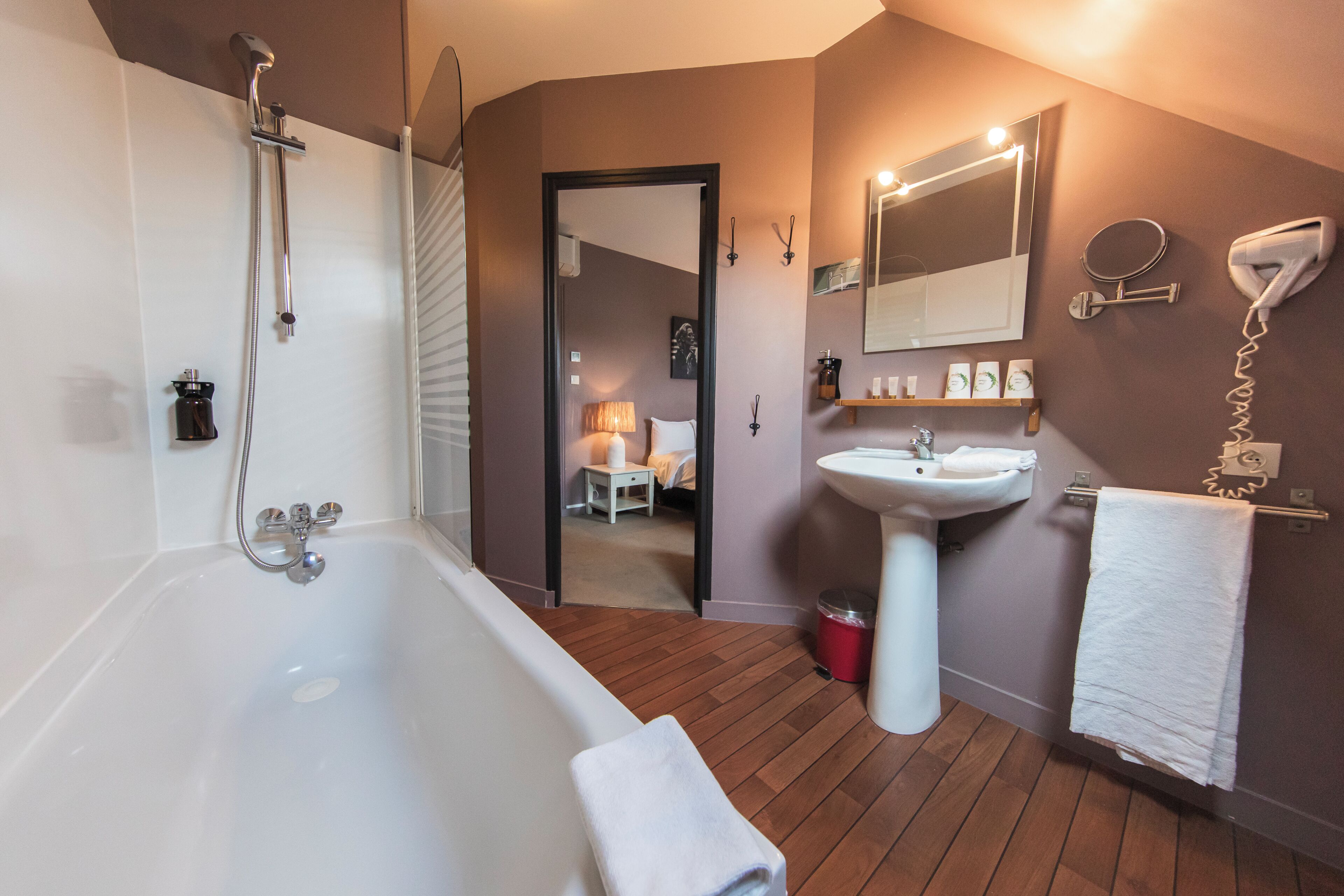 A bathroom with a bathtub, a sink, a mirror, and a hairdryer.