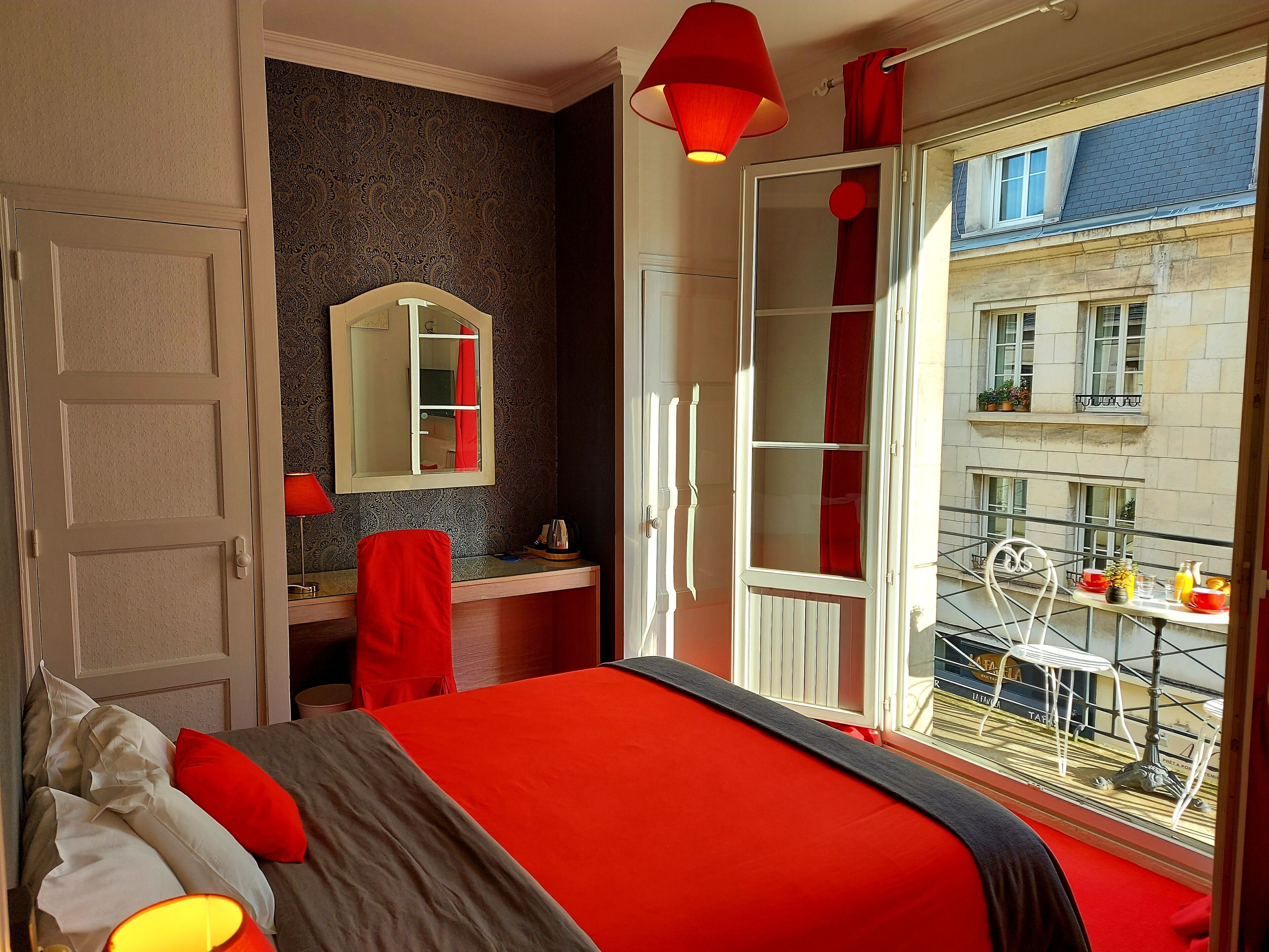 Ein Schlafzimmer mit einem großen Bett, einem Schminktisch, einem Spiegel und einem Fenster mit Balkon.
