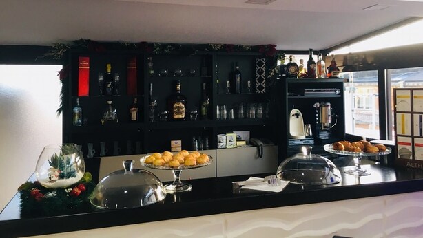 Zona de bar con diversas botellas de licor, vasos y un adorno navideño.