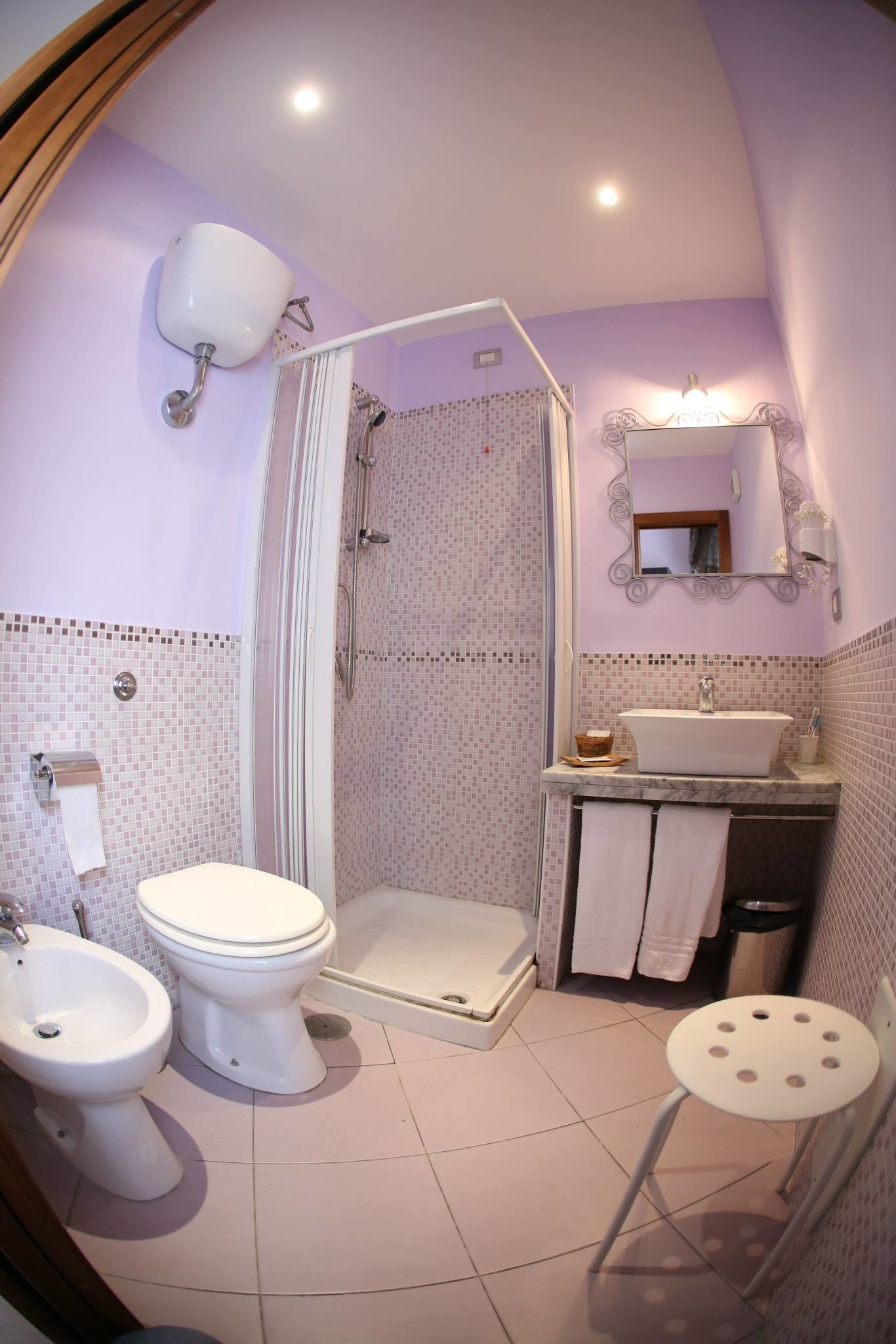 Une salle de bain équipée d’une douche, de toilettes, d’un bidet, d’un lavabo et d’un petit tabouret.
