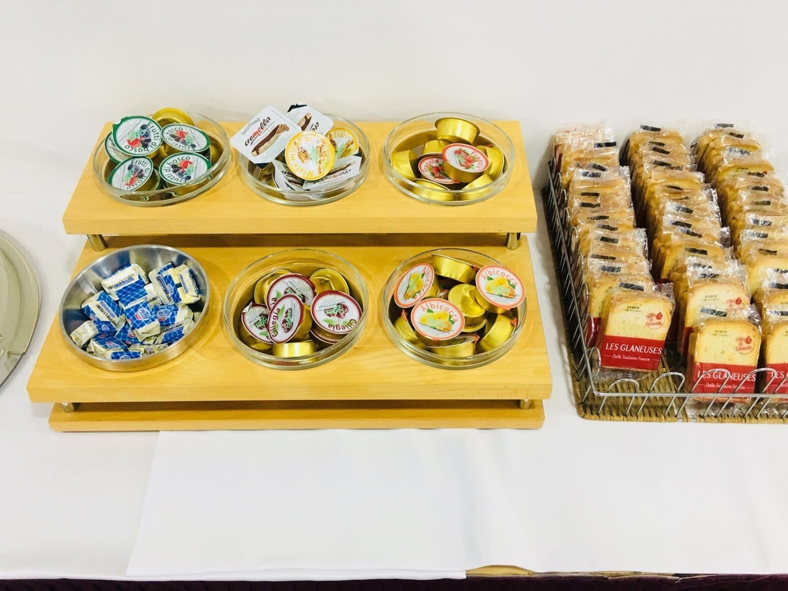 A display of various packaged food items on wooden stands, including jars and bread.