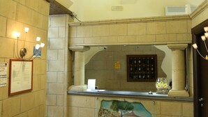 Un área de recepción con piso de baldosas, una barra con un mural, una lámpara colgante y un aviso en el muro.