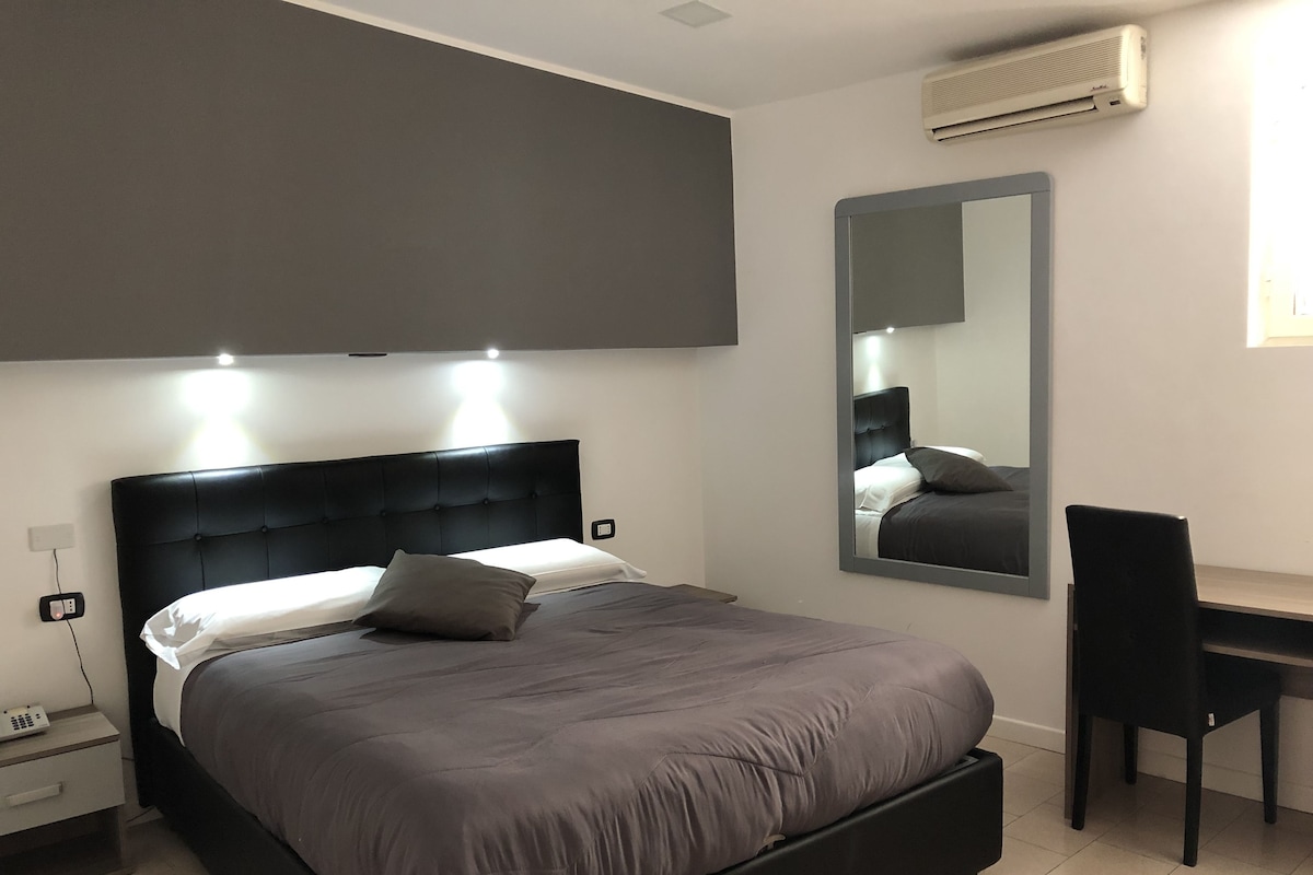 Un dormitorio moderno con una cama grande, una mesita de noche y un escritorio con una silla.
