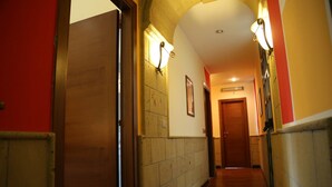 Un pasillo con piso de madera, pared de piedra y una puerta al final.