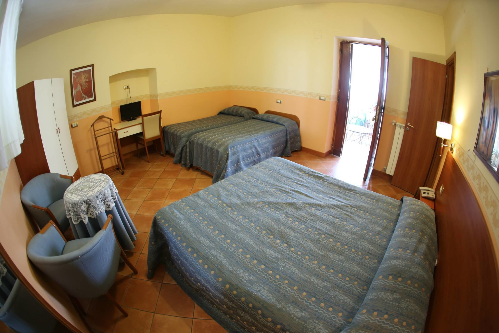Una habitación con dos camas, un escritorio, una silla y un televisor.