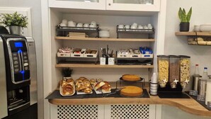 Un buffet de petit-déjeuner avec divers aliments, une machine à café et des étagères de rangement.