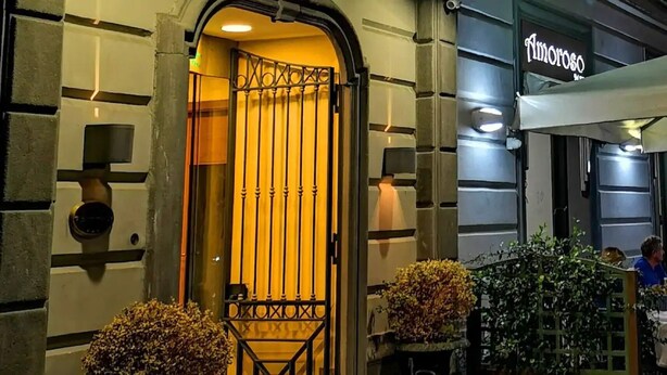 L’entrée d’un hôtel, avec un portail en métal, un intérieur éclairé et des plantes en pot.
