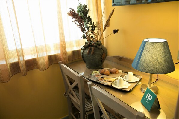 A small dining table with a vase of dried plants, a lamp, and a tray with croissants and cups. - Hotel Potenza (Naples)