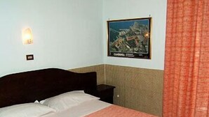 A bedroom with a bed, a nightstand, a wall-mounted light, and a poster on the wall. - Vittorio Veneto (Naples)