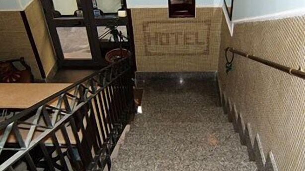 A hotel corridor with a staircase, a door leading outside, and a wall with a 'HOTEL' sign. - Vittorio Veneto (Naples)