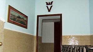 A hallway with a tiled wall, a framed picture, a door with a crown symbol, and a metal railing. - Vittorio Veneto (Naples)
