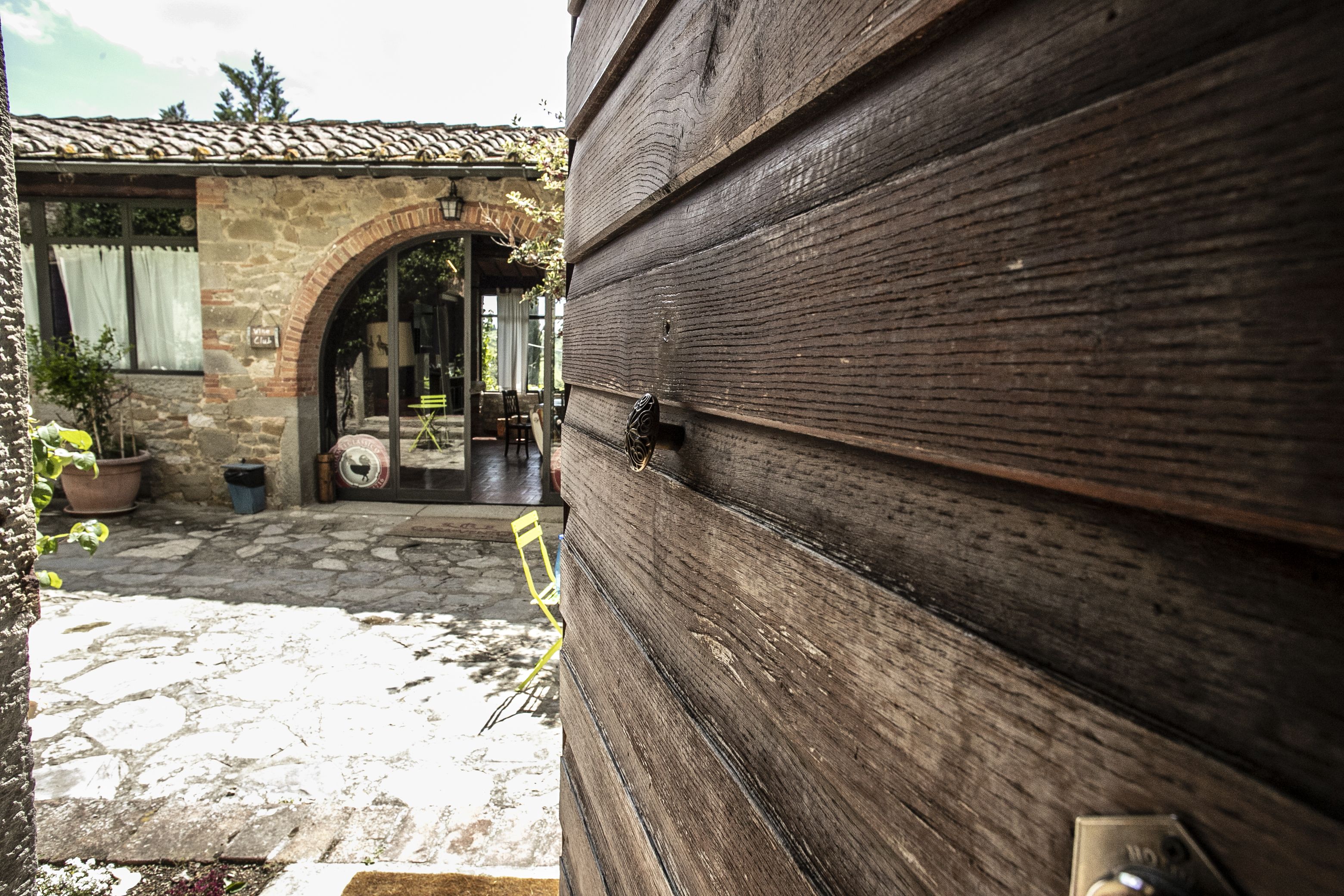 Un bâtiment en pierre avec un toit en tuiles, une porte en bois et un arc en pierre menant à un espace intérieur.