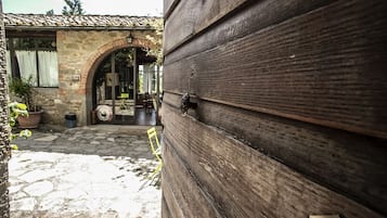 Un bâtiment en pierre avec un toit en tuiles, une porte en bois et un arc en pierre menant à un espace intérieur.